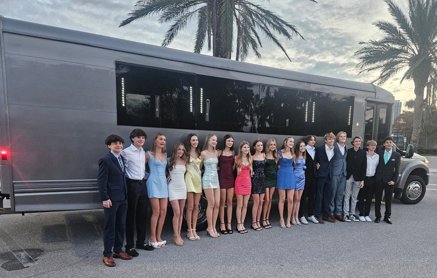 Homecoming group by the party bus at sunset