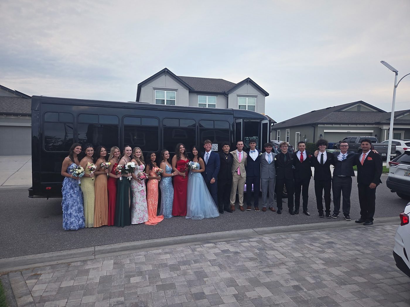 A group in formal wear beside a black Big Time Limo party bus